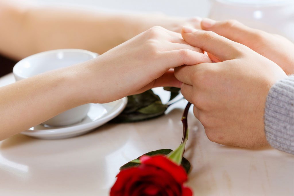 Man and woman on a coffee table with a rose flower