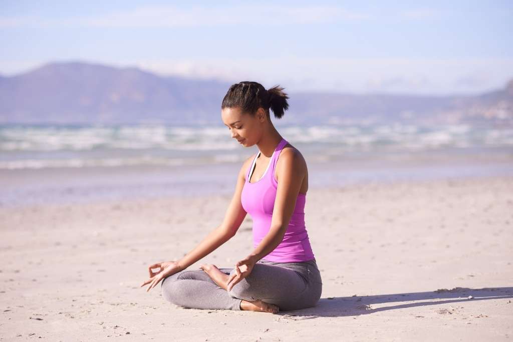 A photo of a beautiful woman on the beach, doing yoga