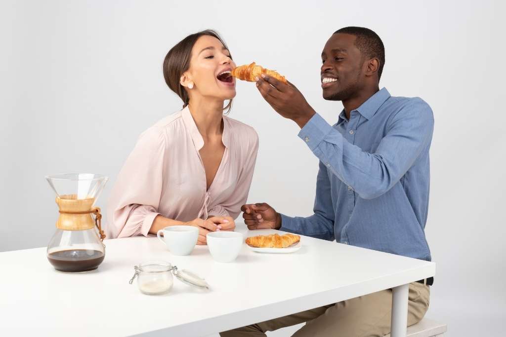 A young beautiful couple eating croissant