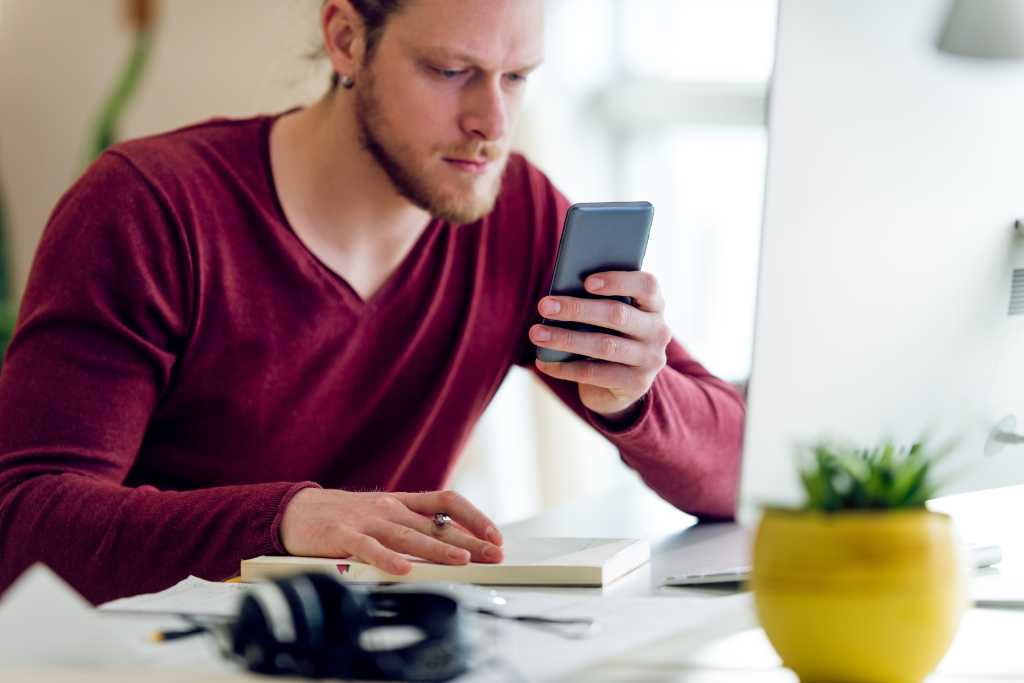 Young man text messages in his office