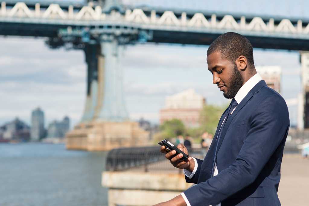 Young business man sending text messages via mobile phone
