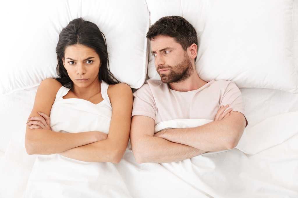husband and wife sitting on the bed unhappy