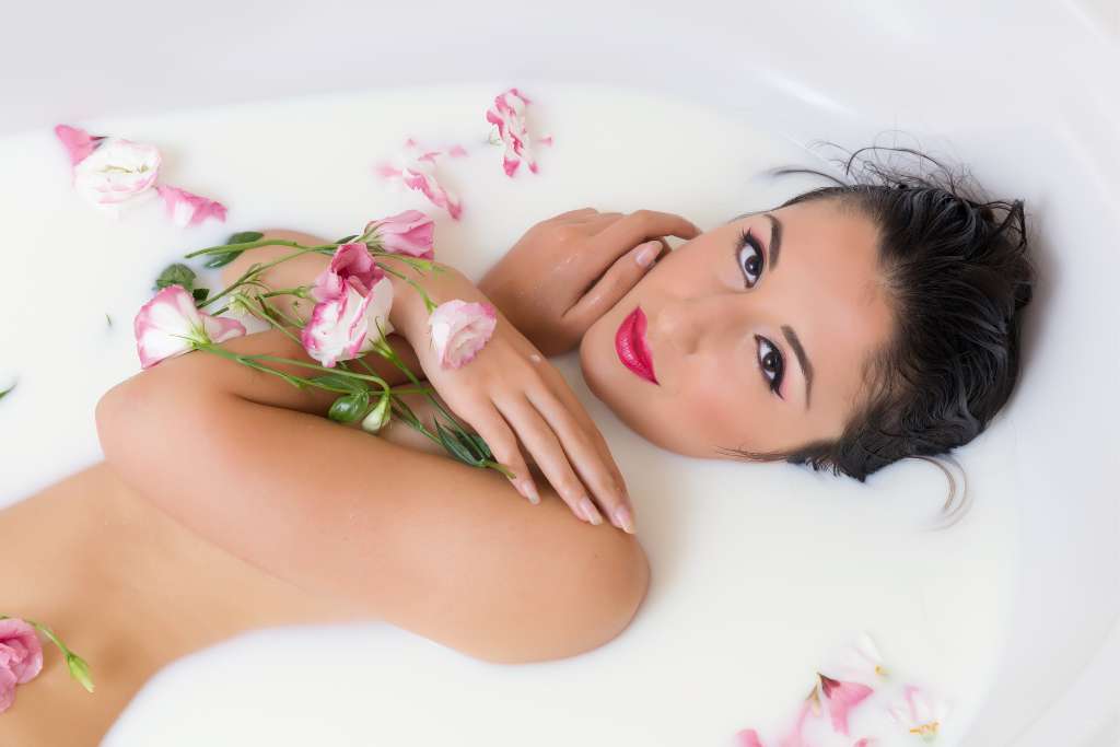 A romantic young woman relaxing in a milk bath with flowers