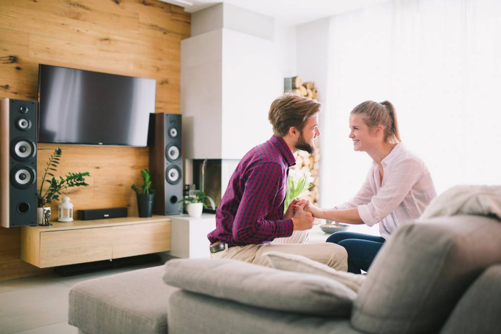 A man and a woman sitting on a couch and holding hands