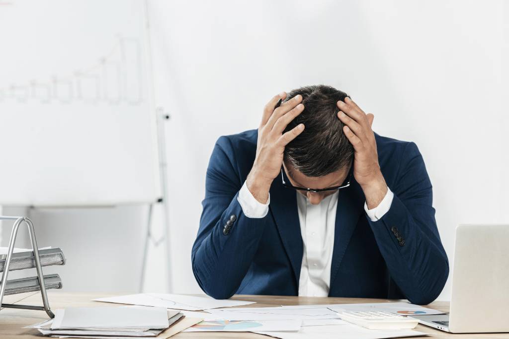 A man sitting at a desk, looking stressed and overwhelmed