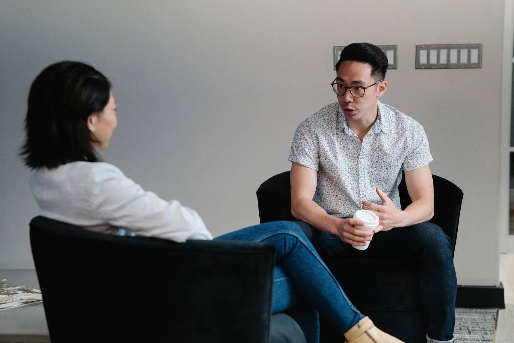 a man and a woman sitting on a couch, talking