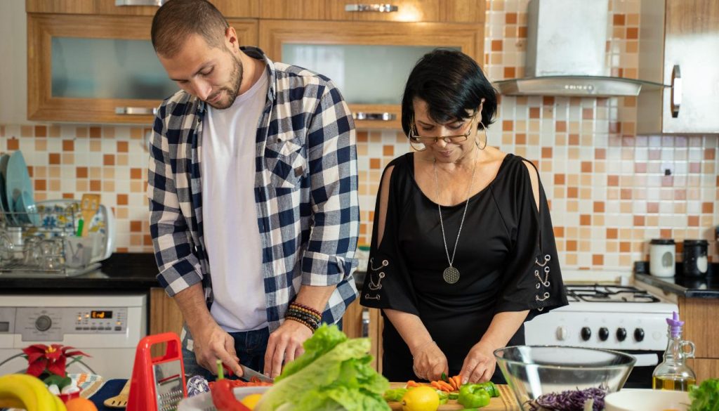 A couple cooking together in the kitchen, chopping ingredients and having a great time.